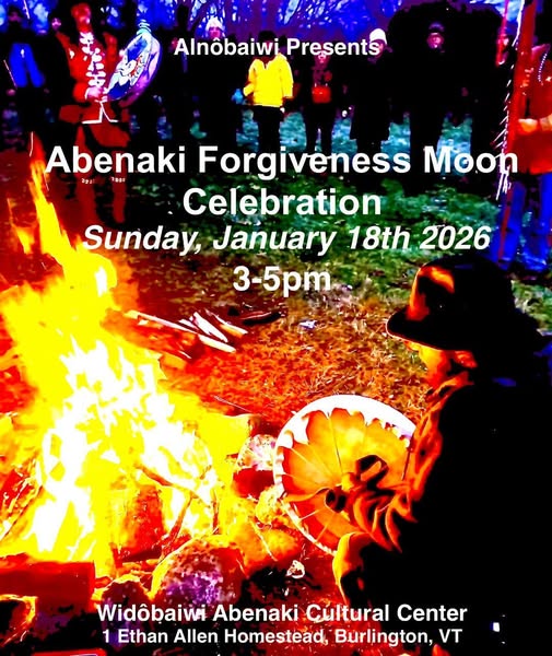 Fire at night with people holding hand drums sitting around it.